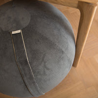 A close-up of a round gray corduroy sitting ball