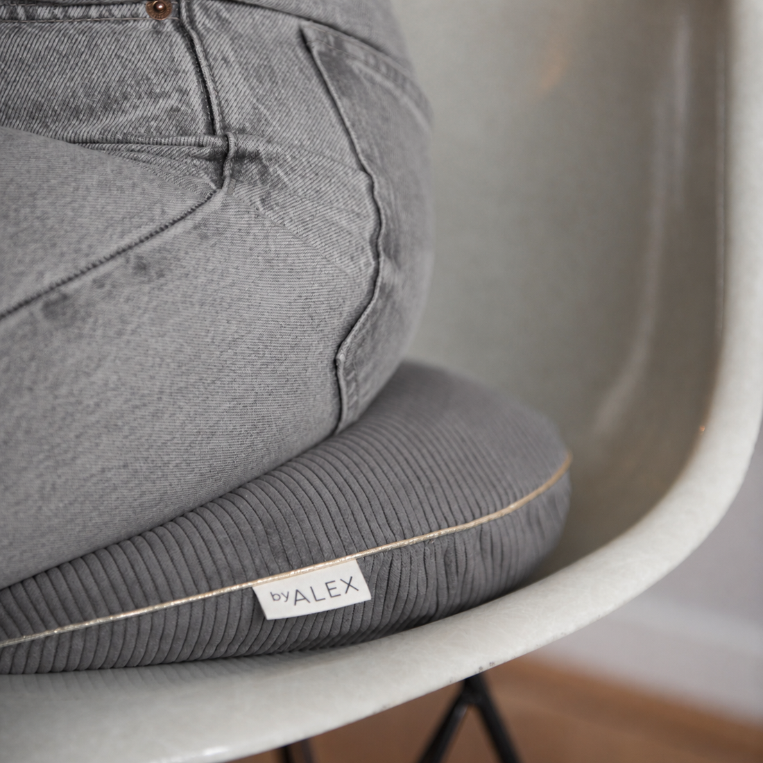 A close-up of a gray ribbed lumbar support cushion with a white &