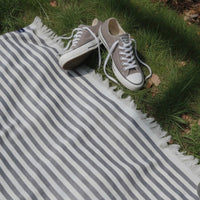 Gray sneakers on a striped towel in a grassy area